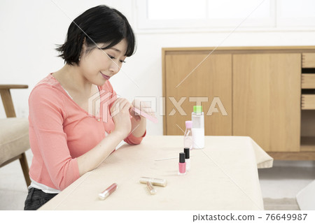 A young woman caring for her nails with a nail file in the room A young woman caring for her nails with a nail file in the room 76649987