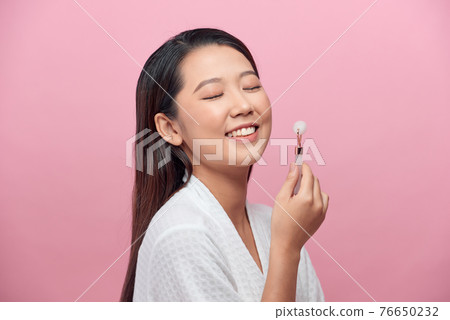 Close up of young woman with rose quartz face roller. She is doing beauty facial massage therapy Close up of young woman with rose quartz face roller. She is doing beauty facial massage therapy 76650232