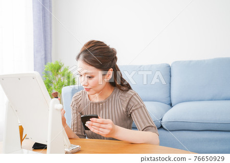 A woman wearing makeup in a room where she lives alone 76650929