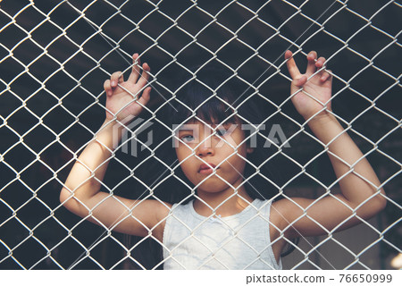 sad Asian girl child alone in cage was imprisoned make no freedom or lack of freedom 76650999