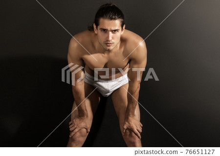Strong stripped muscle male model in gray underwear on black isolated font background 76651127
