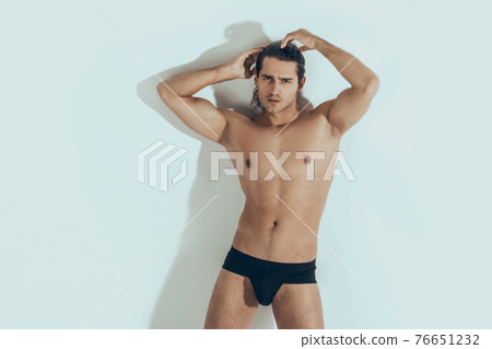 Muscle strong beautiful stripped male model in black underwear on white isolated font background with shadow 76651232