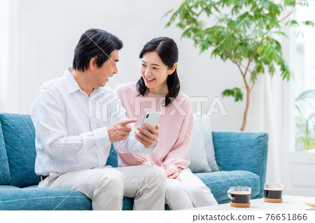 A middle-aged couple watching a smartphone in the living room 76651866