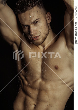 Handsome sport sexy stripped guy portrait in water drops on isolated black background 76652819