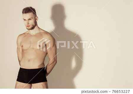 Muscle strong beautiful stripped male model in black underwear on white isolated font background with shadow Muscle strong beautiful stripped male model in black underwear on white isolated font background with shadow 76653227
