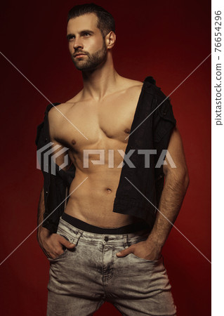 Muscle strong face beautiful stripped male model in casual look with denim on bordo red isolated font background Muscle strong face beautiful stripped male model in casual look with denim on bordo red isolated font background 76654296