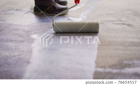 Priming Concrete floor before laying tiles on it, the final preparatory stage for strengthening the surface. Floor priming process. 76654557