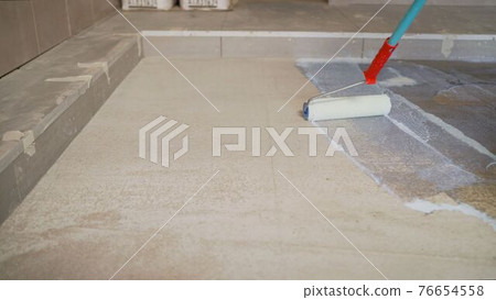 Priming Concrete floor before laying tiles on it, the final preparatory stage for strengthening the surface. Floor priming process. 76654558