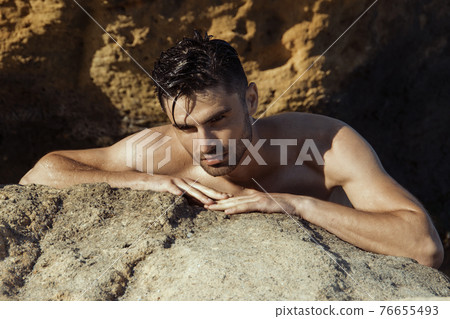 Sexy beautiful striped male model on the nature background with sand and sky on the beach on the sunset Sexy beautiful striped male model on the nature background with sand and sky on the beach on the sunset 76655493