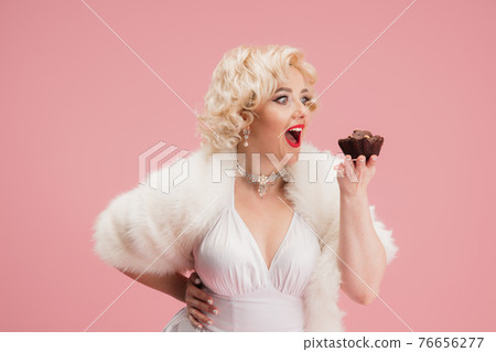 Portrait of young woman in white dress on coral pink background. Female model as a legendary actress. Pin up. Concept of comparison of eras, modern, fashion, beauty. Portrait of young woman in white dress on coral pink background. Female model as a legendary actress. Pin up. Concept of comparison of eras, modern, fashion, beauty. 76656277