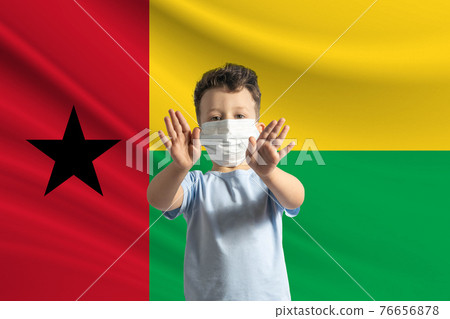 Little white boy in a protective mask on the background of the flag of Guinea-Bissau. Makes a stop sign with his hands, stay at home Guinea-Bissau Little white boy in a protective mask on the background of the flag of Guinea-Bissau. Makes a stop sign with his hands, stay at home Guinea-Bissau 76656878