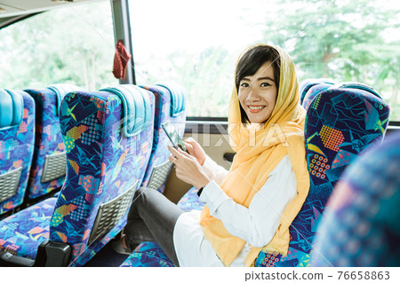 muslim woman doing eid mubarak traveling back to her hometown by riding a bus muslim woman doing eid mubarak traveling back to her hometown by riding a bus 76658863
