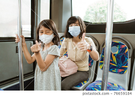 a woman with a thumbs up and a little girl with a hand gesture symbolizes love when wearing a mask a woman with a thumbs up and a little girl with a hand gesture symbolizes love when wearing a mask 76659184
