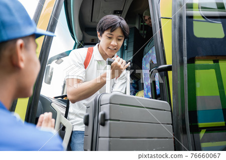 A handsome man with rucksack and suitcase walking out from travel bus 76660067