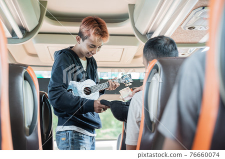 a passenger gives money to a busker wearing an ukulele 76660074
