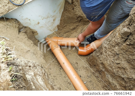The contractor installs a sewer in a ditch and leads the pipe to the sump. The contractor installs a sewer in a ditch and leads the pipe to the sump. 76661942