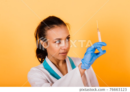 Portrait of beautiful African American doctor or nurse isolated over yellow background 76663123