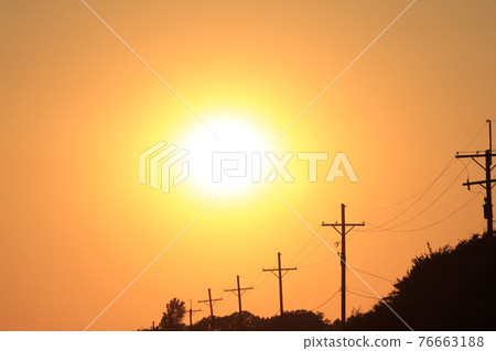 Power lines and poles at Sunset out in the country with the sun and a colorful sky in Kansas. Power lines and poles at Sunset out in the country with the sun and a colorful sky in Kansas. 76663188