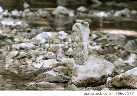 Stacked rocks, balancing in a streambed. Balanced rock pile at a creek, with a small red ladybug on top, surrounded by a creek. Rocks laid flat upon each other. Art form and leisure activity. Photo. Stacked rocks, balancing in a streambed. Balanced rock pile at a creek, with a small red ladybug on top, surrounded by a creek. Rocks laid flat upon each other. Art form and leisure activity. Photo. 76663577