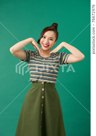 Beautiful young Asian girl smiling sweetly putting her palm on her chin Beautiful young Asian girl smiling sweetly putting her palm on her chin 76672976