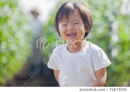 A farmer's mother working in the field and a child playing in the field 76674093