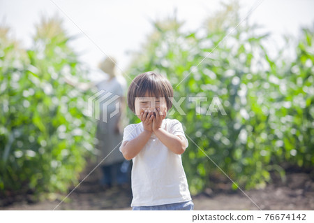 A farmer's mother working in the field and a child playing in the field 76674142