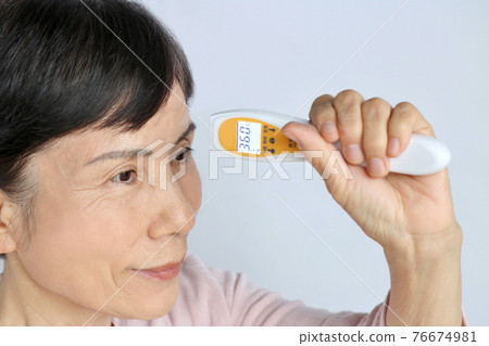 使用非接觸式溫度計、正溫度計的高級女性 76674981