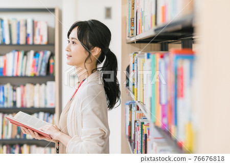 Young woman reading a book in the library 76676818