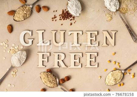 Metal spoons of various gluten free flour almond, oatmeal, buckwheat, rice, corn and gluten free lettering made of wooden letters, flat lay, top view 76678158