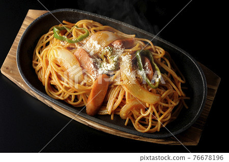 A hot Neapolitan with onions, peppers, and wieners on an iron plate taken on a black background (overhead view) A hot Neapolitan with onions, peppers, and wieners on an iron plate taken on a black background (overhead view) 76678196