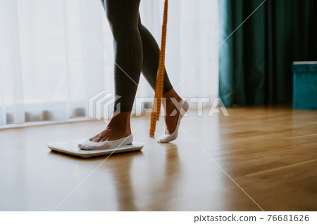 Woman Measuring Body Weight On Weighing Scale At Home.  76681626