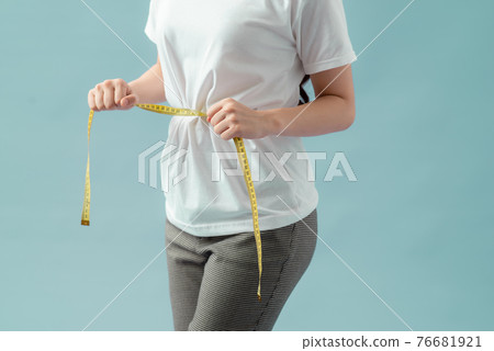 Women healthy body care weight control measuring waist fat using tape measure or measuring tape. 76681921