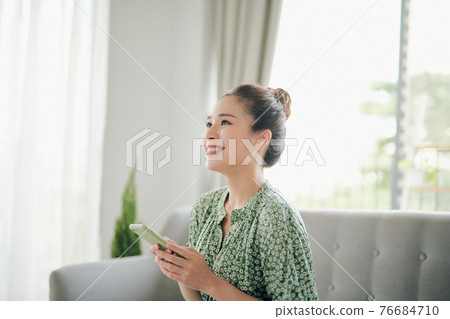 Smiling young girl using funny mobile app laughing, playing game, chatting on cell at home. Smiling young girl using funny mobile app laughing, playing game, chatting on cell at home. 76684710