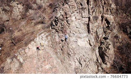 A group of people are engaged in rock climbing. 76684773