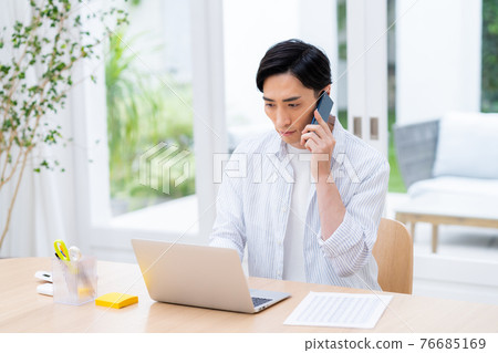 一個通過遠程辦公打電話的年輕商人 一個通過遠程辦公打電話的年輕商人 76685169