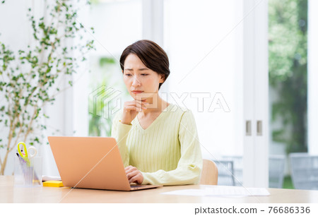 Middle-aged woman suffering from telework Middle-aged woman suffering from telework 76686336