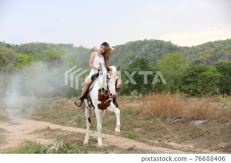 Women on skirt dress Riding Horses On field landscape Against Sky During Sunset Women on skirt dress Riding Horses On field landscape Against Sky During Sunset 76688406