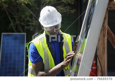 maintenance engineer, Solar energy systems engineer perform analysis solar panels, Portrait of engineer man or worker, people, with solar panels or solar cells on the roof in farm. Power plant with maintenance engineer, Solar energy systems engineer perform analysis solar panels, Portrait of engineer man or worker, people, with solar panels or solar cells on the roof in farm. Power plant with 76689370