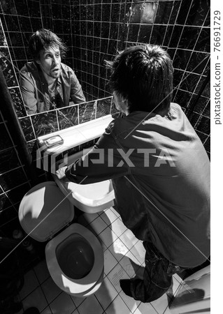 Drunk Man looks at himself in the mirror 76691729