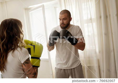 Man wearing gloves defend oneself while having boxing training with his wife 76692007