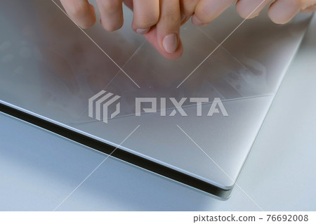 A woman's hand removes the film from a new laptop, closeup view. 76692008