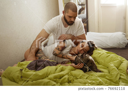 Stroking dog while laying on the bed in modern apartments 76692118