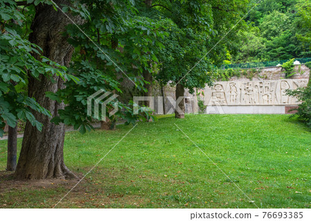 Trees and monument in the city park Stadtpark, a green island in the middle of the city, in Graz, Styria region, Austria. 76693385