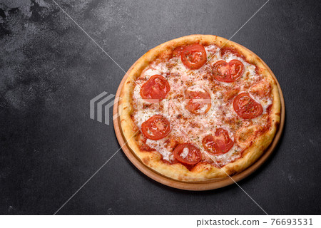 Tasty fresh oven pizza with tomatoes, cheese and basil on a concrete background 76693531