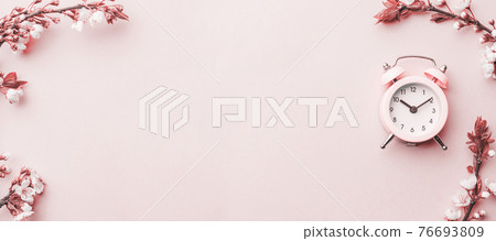 Spring time flowers blossom and may flowers with alarm clock on pink. For banner, branches of blossoming cherry against background. Dreamy romantic image, landscape panorama, copy space. 76693809