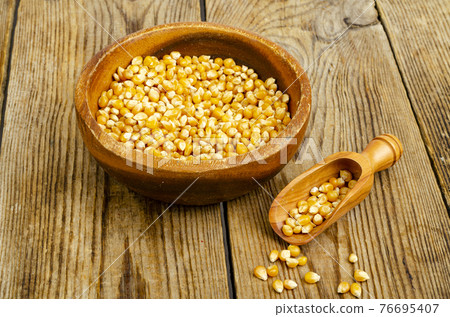 Dry corn grains in bowl for making popcorn. 76695407