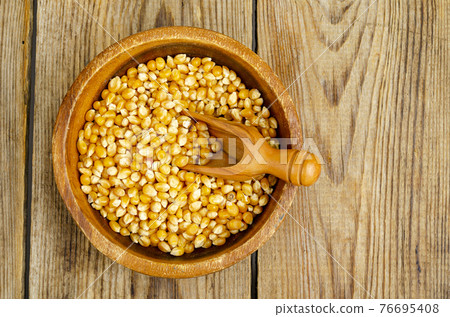 Dry corn grains in bowl for making popcorn. 76695408