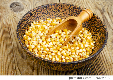 Dry corn grains in bowl for making popcorn. 76695409