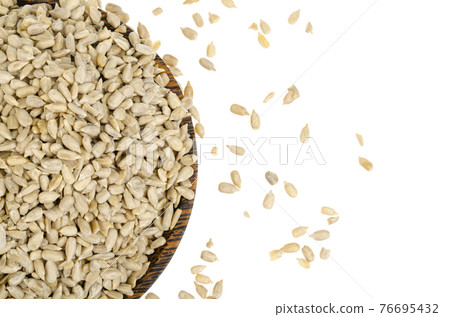 Hullled sunflower seeds pile in bowl on white background. Hullled sunflower seeds pile in bowl on white background. 76695432