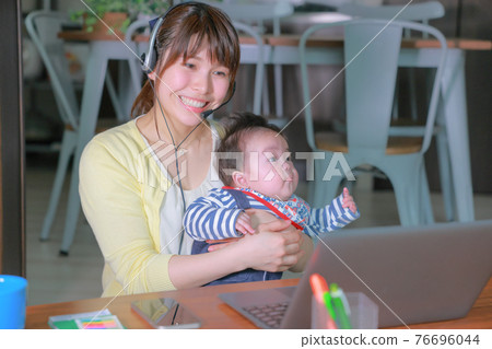 Woman in online meeting with baby and smile Woman in online meeting with baby and smile 76696044
